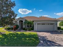 Charming home with a well-manicured lawn, mature landscaping and brick-paved driveway leading to the attached two-car garage at 4232 Roebelenii Dr, Lake Wales, FL 33859