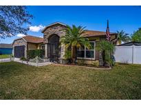 Charming single-story home featuring stone accents, a screened entrance, a well-manicured lawn, and mature palm trees at 625 Hatchwood Dr, Haines City, FL 33844