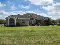 Charming single-story home featuring manicured lawn, arched windows, and symmetrical landscaping under a blue sky at 1408 Hidden Creek Ln, Winter Haven, FL 33880