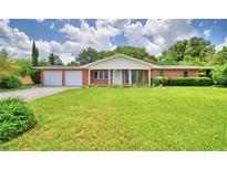 Charming brick home featuring a spacious front yard, manicured landscaping, and a two-car garage at 1475 S Lake Howard Dr, Winter Haven, FL 33880