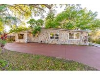Charming single-story home featuring a stone facade, mature trees, and a spacious driveway at 3027 Maplewood Ave, Lakeland, FL 33803