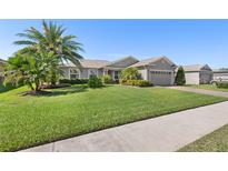 Beautiful single Gathering home with lush landscaping, mature palm trees, and a manicured lawn at 462 Lake View Way, Auburndale, FL 33823