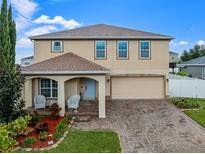 Two-story home with brick driveway, attached two car garage, covered porch and landscaped flowerbeds at 10234 Lenox St, Clermont, FL 34711