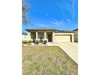 Charming single-story home featuring a well-maintained lawn, inviting front porch and attached two car garage at 1056 Naes Ln, Lake Wales, FL 33853