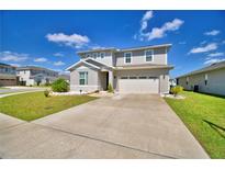 Charming two-story home features a well-manicured lawn, concrete driveway, and a two-car garage at 1091 Sugarwood St, Davenport, FL 33837