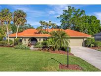 Charming home featuring a red tile roof, lush landscaping, and a well-manicured lawn at 1116 Cypress W Pt, Winter Haven, FL 33884