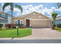 Charming single-Gathering home with a well-manicured lawn, beautiful landscaping, and a brick paver driveway at 225 Highgate Park Blvd, Davenport, FL 33897