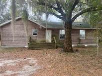 Exterior view of a single story home with wood siding and front yard with tree at 261 Acacia Walk, Lake Wales, FL 33898