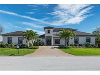 Elegant home featuring a symmetrical design, manicured landscaping, and a brick driveway with a welcoming entrance at 4717 Emerald Palms Ct, Winter Haven, FL 33884