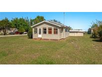 Quaint one-story home with a manicured lawn, tan siding, and welcoming front porch at 555 Morrel Ave, Lake Wales, FL 33859