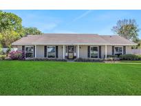 Charming single-story home featuring a well-manicured lawn, tidy landscaping, and neutral brickwork under a sunny, blue sky at 67 Alachua Dr, Winter Haven, FL 33884