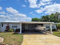 Charming home with a boat parked in the carport, under a bright blue sky at 121 Bonnie Dr, Auburndale, FL 33823