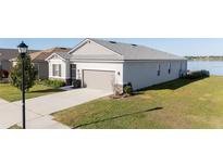 Beautiful single-Gathering home with gray stucco, stone accents, attached garage, and lovely lawn at 169 Summershore Dr, Auburndale, FL 33823