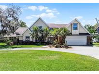 Charming two-story home featuring a spacious front yard, palm trees, and an attached two-car garage at 2 Bridgewater Dr, Winter Haven, FL 33884