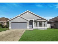 Charming one-story home boasts a well-maintained lawn and a two car garage with a gray exterior paint at 4099 Island Lakes Dr, Winter Haven, FL 33881