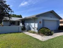Inviting home featuring a light blue exterior, attached garage, and well-maintained front yard at 460 Pinehurst Ct, Winter Haven, FL 33884