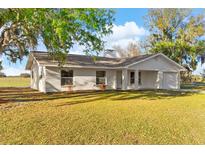 Charming single-story home with a white exterior, well-manicured lawn, and classic architectural details at 6430 Russo Rd, Bartow, FL 33830