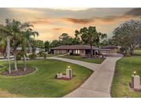 Charming ranch-style home featuring a spacious driveway, well-manicured lawn, and mature landscaping including palm trees at 8947 Oakwood Dr, Lake Wales, FL 33898