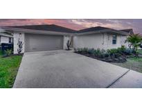 Charming single-story home with a gray two-car garage, white stucco, and a well-manicured lawn at 409 Greenfield Rd, Winter Haven, FL 33884