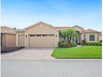 Charming single-story home with a well-manicured lawn, brick driveway, and attached two-car garage at 5200 Pebble Beach Blvd, Winter Haven, FL 33884