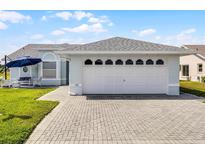 Traditional-style home featuring a two-car garage with a brick paved driveway and manicured lawn at 530 Eastlake Dr, Haines City, FL 33844