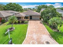 Charming home boasts a brick driveway, lush lawn, and mature landscaping at 571 Saint Andrews Rd, Winter Haven, FL 33884