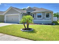 Charming single-story home featuring a stone facade, two-car garage, and a well-manicured front lawn with palm tree accent at 8243 Campbell Crossing Cir, Lakeland, FL 33810