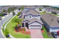 Charming two-story home with a well-manicured lawn, brick driveway, and attached two-car garage in a quiet community at 825 Grazie Loop, Davenport, FL 33837
