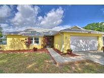 Charming single-story home with a well-manicured lawn, colorful plants, and a two-car garage at 103 Lake Thomas Dr, Winter Haven, FL 33880