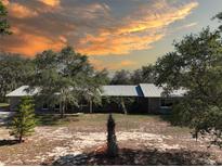 Charming single-story home featuring mature trees and a metal roof, set against a colorful sunset sky at 1432 Libby Rd, Babson Park, FL 33827