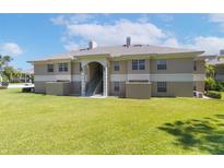 Back of the condo with green lawn and stairs to second floor units at 1602 Eagle Pond Dr # 1602, Winter Haven, FL 33884