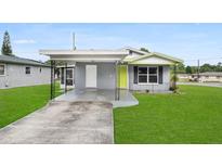 Charming single-story home with a grey exterior, well-maintained lawn, and a covered carport at 2020 Bassedena W Cir, Lakeland, FL 33805