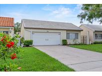 Charming home featuring a white tile roof, well-manicured lawn, and attached two-car garage at 259 Mariposa, Winter Haven, FL 33884