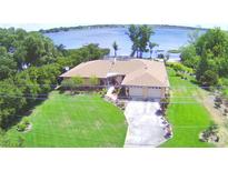 Aerial view of lakeside house with manicured lawn, mature trees, and a long driveway at 2611 State Road 557, Lake Alfred, FL 33850