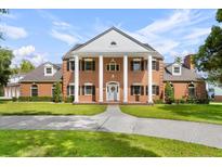 Stately brick home featuring large white columns, dormer windows, a manicured lawn and mature landscaping at 3826 Gaines Ct, Winter Haven, FL 33884