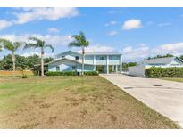 Stunning two-story home with a metal roof, light blue siding and a well-maintained lawn with palm trees at 6925 Alturas Babson Park Cutoff, Bartow, FL 33830