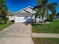 Charming single-Gathering home featuring a two-car garage, well-manicured lawn, and mature palm trees at 8001 Arrow Creek Rd, Kissimmee, FL 34747
