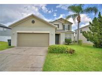 Charming two-story home with a well-maintained lawn, a two-car garage, and a palm tree at 154 Canna Dr, Davenport, FL 33897