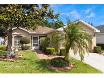Charming home featuring well-manicured landscaping, mature trees and a brick walkway leading to a screened front entrance at 284 Lake Suzanne Dr, Lake Wales, FL 33859