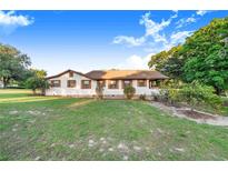Charming one-story home featuring symmetrical design, white siding, and beautiful mature trees and landscaping at 302 W Gates Ave, Lake Hamilton, FL 33851