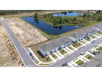 An aerial view showcases new townhomes in a community with a scenic pond and available lots at 3281 Vesara, Davenport, FL 33837