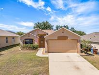 Charming single-story home with a two-car garage, well-manicured lawn, and neutral color palette at 533 Ronshelle Ave, Haines City, FL 33844