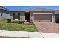 Charming single-story home featuring a brick driveway, manicured lawn and neutral color palette at 625 Disa Dr, Davenport, FL 33837