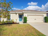 Charming single-story home featuring a well-manicured lawn, a blue front door, and an attached two-car garage at 213 Tanager St, Haines City, FL 33844