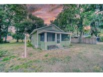 Charming, green cottage-style home with a screened-in porch and mature trees at 230 Denton Ave, Auburndale, FL 33823