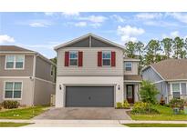 Charming two-story home with gray siding, brick driveway, red shutters, and well-maintained landscaping at 2356 Palm Park Loop, Clermont, FL 34714