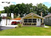 Charming bungalow featuring a covered parking area, a white picket fence, and well-maintained landscaping at 418 E 10Th Ave, Mount Dora, FL 32757