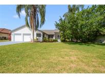 Charming single-story home with a lush green lawn, mature trees, and a two-car garage at 6014 Crystal View Dr, Orlando, FL 32819