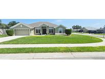 Well-manicured front yard of a single-story home featuring a lush green lawn, complemented by a paved driveway and sidewalk at 1400 Eagle Crest Blvd, Winter Haven, FL 33881