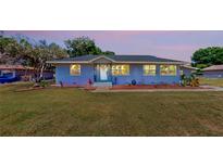 Charming blue home boasts a well-manicured lawn and inviting entryway with a sidewalk and a landscaped garden at 1515 W Lake Cannon Nw Dr, Winter Haven, FL 33881